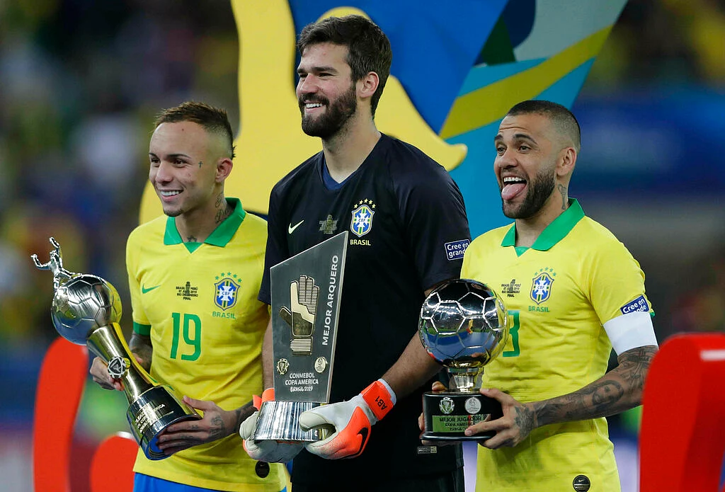 Brazil's Everton, left, holds his Top Scorer trophy as he poses with teammates goalkeeper Alisson holding his Best Goalkeeper trophy and Brazil's Dani Alves holding his top scorer trophy.