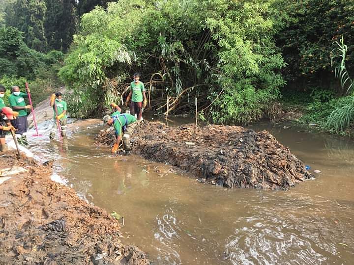 ஆற்றில் குவிந்துள்ள குப்பைகளை அகற்றும் மக்கள்