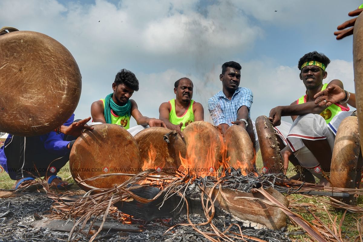 நெருப்பு மூட்டி பறையை முறுக்கேற்றும் இசைக்கலைஞர்கள்