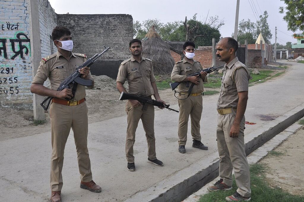 Policemen stand guard after a gang of criminals ambushed and fired on police who had come to arrest them in Kanpur, India, Friday, July 3, 2020.
