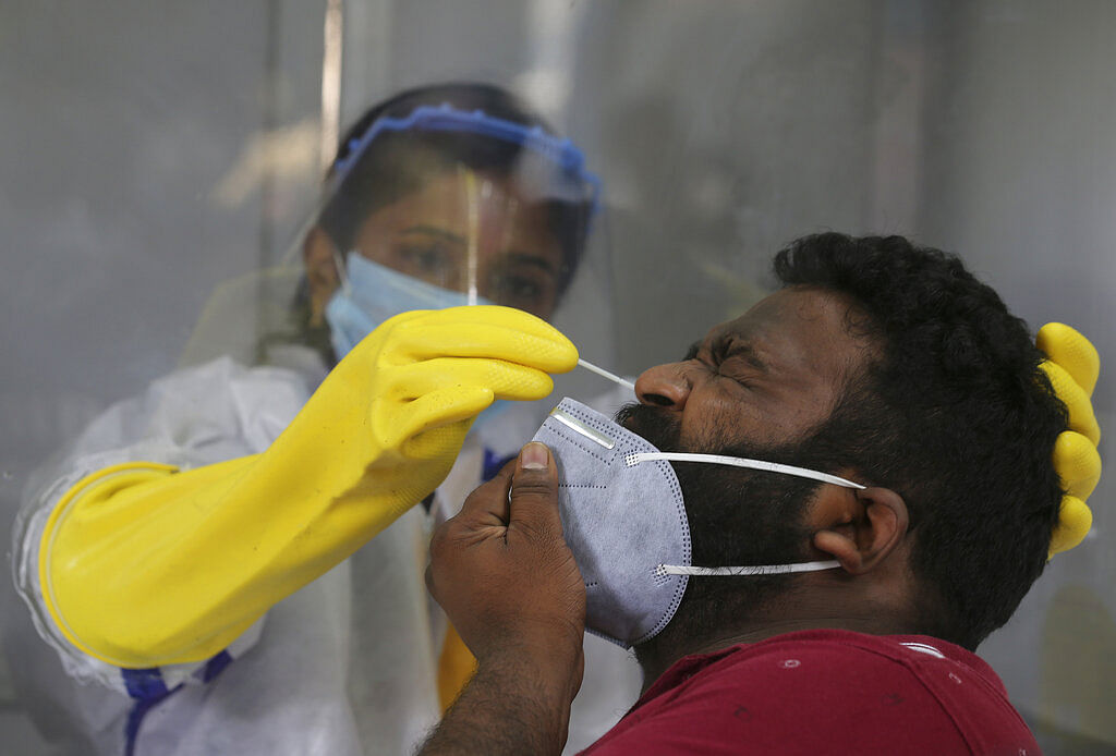 A health worker takes a nasal swab sample to test for COVID-19