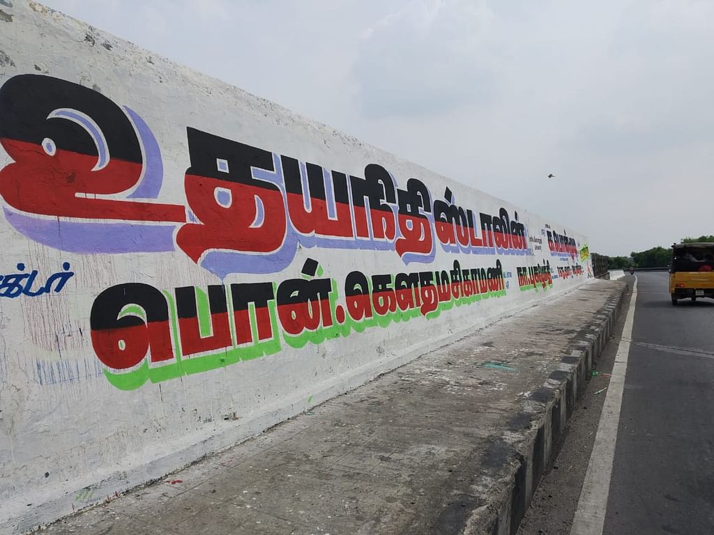 சாலையோர தடுப்பு சுவரில் எழுதப்படும் சுவர் விளம்பரம்.