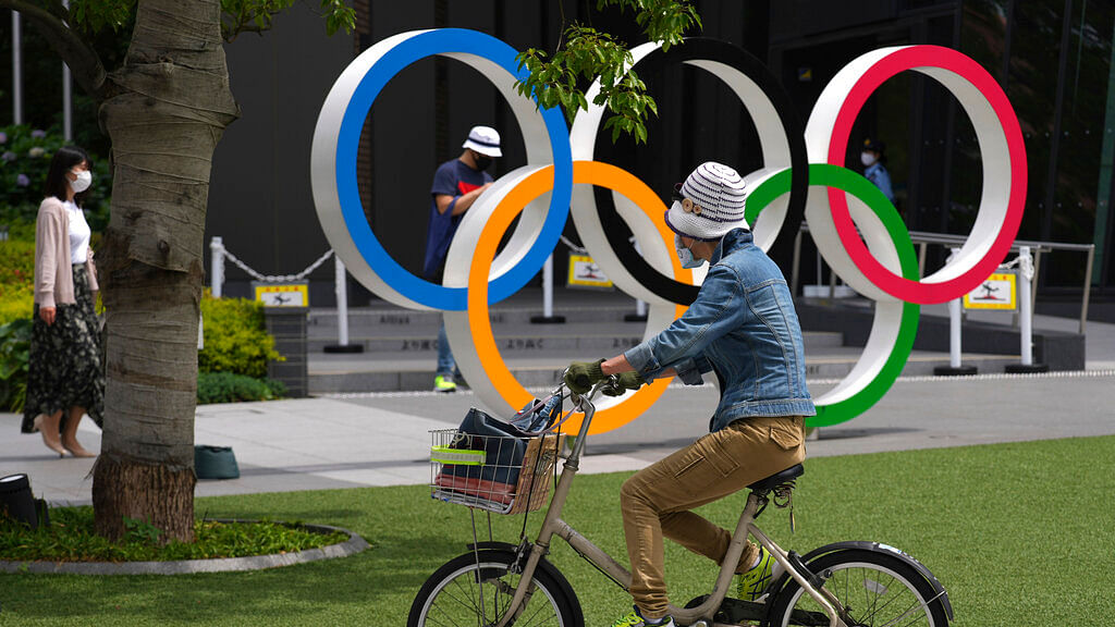 A woman rides a bicycle near the Olympic Rings