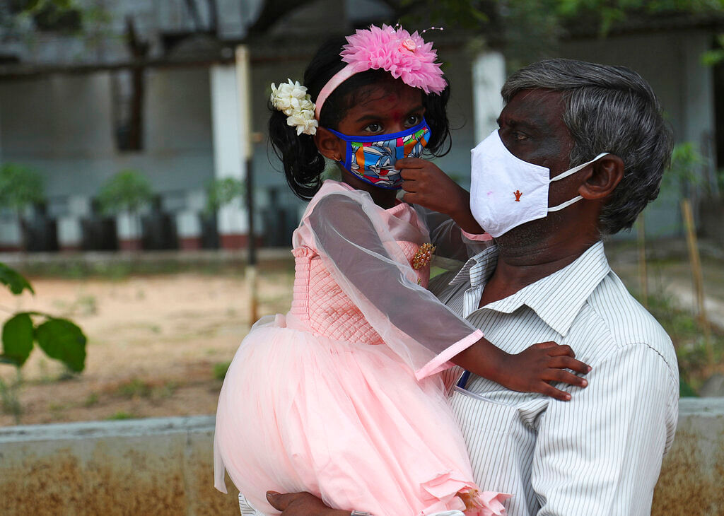 A man carries his granddaughter wearing face masks