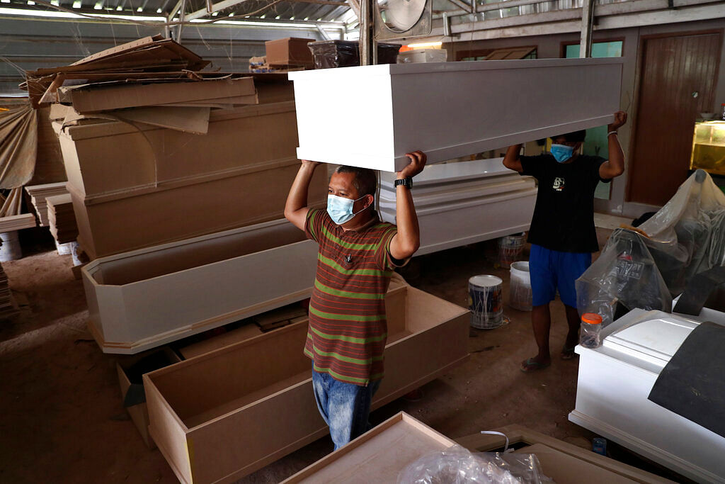 Workers wearing mask to curb the spread of coronavirus carry a coffin specially made for burial with COVID-19 protocol at their workshop in Jakarta, Indonesia