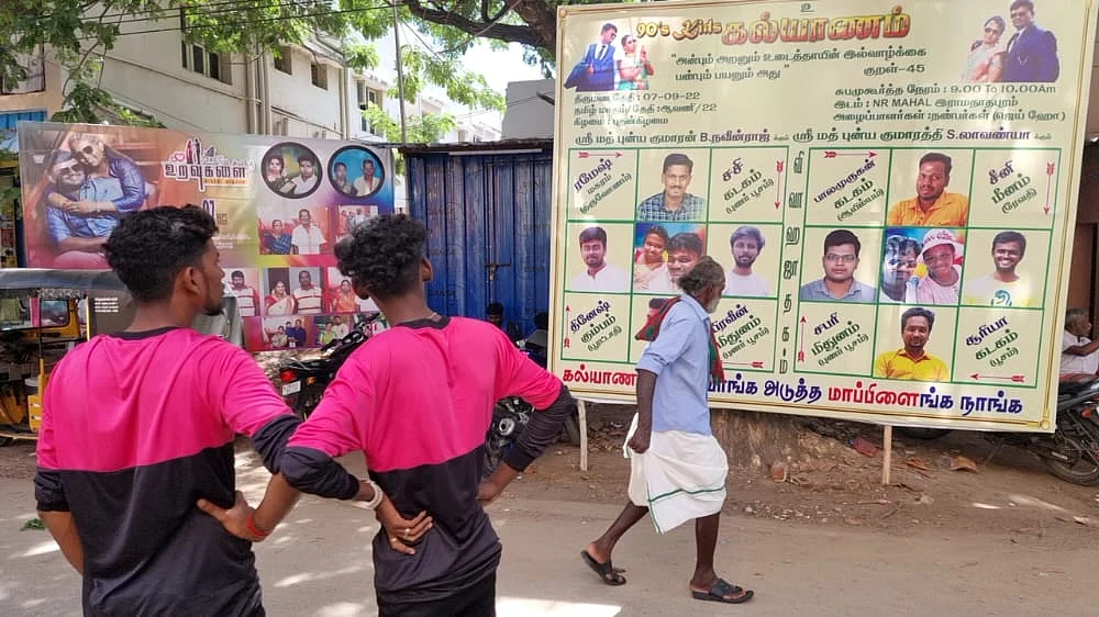 பேனரை பார்க்கும் முதியவர் மற்றும் இளைஞர்கள்